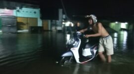 FOTO: Salah seorang warga Kota Sampit yang berjalan melalui banjir di Jalan DI Panjaitan, Kabupaten Kotim. (FOTO: BUDDI). 