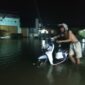FOTO: Salah seorang warga Kota Sampit yang berjalan melalui banjir di Jalan DI Panjaitan, Kabupaten Kotim. (FOTO: BUDDI). 