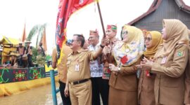 FOTO: Plh Asisten Pemkesra Herson B Aden mengibarkan bendera tanda dimulainya lomba perahu hias dalam rangka Festival Budaya Isen Mulang (FBIM). (FOTO: IST) 