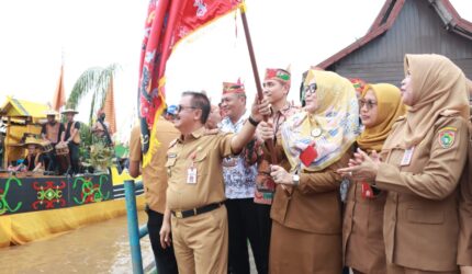 FOTO: Plh Asisten Pemkesra Herson B Aden mengibarkan bendera tanda dimulainya lomba perahu hias dalam rangka Festival Budaya Isen Mulang (FBIM). (FOTO: IST) 