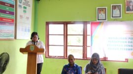 FOTO: Plt. Kepala BIdang Perlindungan Perempuan dan Kualitas Keluarga Mariana saat membacakan sambutan pada acara sosialisasi pergub di Kantor Balai Desa Pamait Kabupaten Barito Selatan