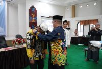 MENGALUNGKAN : Plt Kepala Biro Kesra Setda Kalteng Ahmad Pahruka saat mengalungkan tanda kepesertaan umrah kepada salah satu jamaah saat kegiatan manasik haji di Aula Asrama Haji Al Mabrur, Kamis (6/3). (IST)