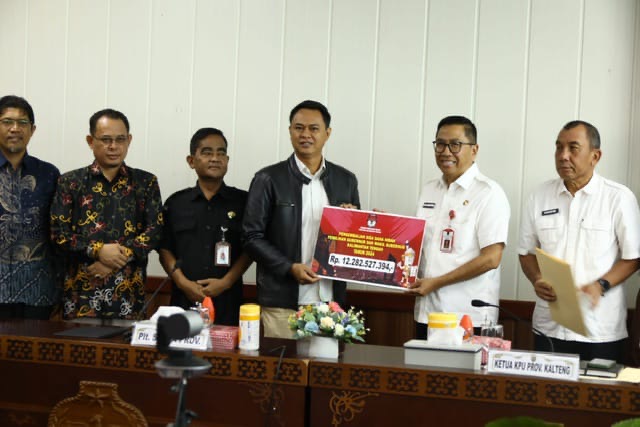 MENYERAHKAN: Ketua KPU Provinsi Kalteng Sastriadi saat menyerahkan secara simbolis sisa dana sebesar Rp12.282.527.394,- kepada Plt. Sekretaris Daerah Prov. Kalteng Leonard S. Ampung dalam sebuah seremoni di Ruang Rapat Bajakah Kantor Gubernur, Rabu (7/5).(IST)