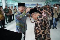 MENYAMBUT : Gubernur Provinsi Kalteng H. Agustiar Sabran saat memasangkan lilis lamiang kepada Menteri Pendidikan Dasar dan Menengah Abdul Mu’ti sebagai simbol penyambutan saat di Bandara Tjilik Riwut, Palangka Raya, Jumat (9/5).(IST)