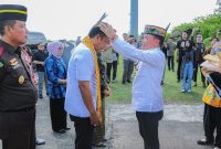 PASANGKAN : Gubernur Kalteng H. Agustiar Sabran saat memasangkan lawung kepada Kepala Kejaksaan Tinggi Kalimantan Tengah yang baru Agus Sahat Sampe Tua Lumban Gaol, dalam prosesi penyambutan adat di Bandara Tjilik Riwut Palangka Raya, Jumat (18/7/2025).(IST)
