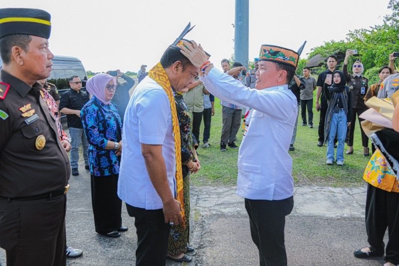 PASANGKAN : Gubernur Kalteng H. Agustiar Sabran saat memasangkan lawung kepada Kepala Kejaksaan Tinggi Kalimantan Tengah yang baru Agus Sahat Sampe Tua Lumban Gaol, dalam prosesi penyambutan adat di Bandara Tjilik Riwut Palangka Raya, Jumat (18/7/2025).(IST)