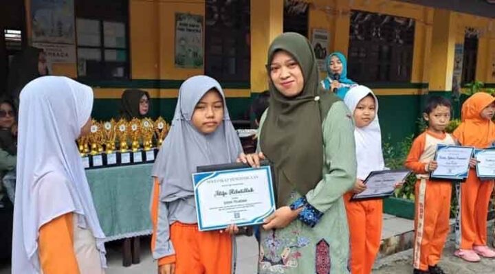 PENYERAHAN: Salah satu guru saat menyerahkan piagam bagi siswa SDN 7 Baamang Hilir yang berprestasi, Kamis (31/7/2025).(IST)
