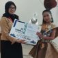 JUARA : Siswi SDN 4 Ketapang Nafisa Qirla Rindani saat menerima hadiah sebagai Juara I dalam Featival Lomba Busana Daur Ulang Universitas Darwan Ali Sampit, Sabtu, (8/3/2025).(IST)