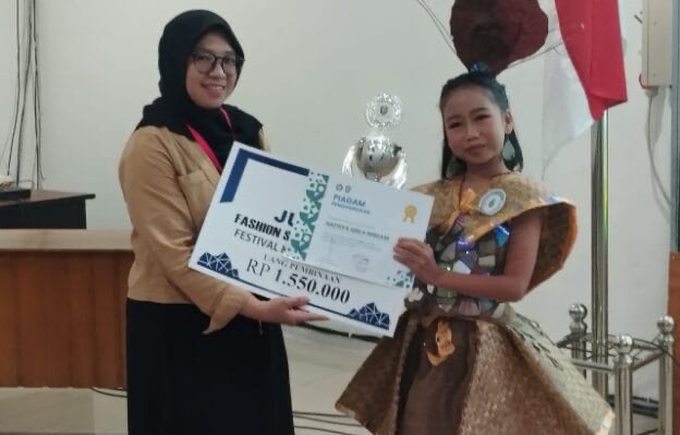 JUARA : Siswi SDN 4 Ketapang Nafisa Qirla Rindani saat menerima hadiah sebagai Juara I dalam Featival Lomba Busana Daur Ulang Universitas Darwan Ali Sampit, Sabtu, (8/3/2025).(IST)