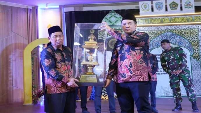 SERAHKAN : Bupati Lamandau, Rizki Aditya Putra menyerahkan piala bergilir kepada panitia saat membuka Musabaqah Tilawatil Qur’an dan Hadits (MTQH) XII Tingkat Kabupaten Lamandau Tahun 2025, di Gedung Lantang Torang, Minggu (21/9/2025) malam.(IST)