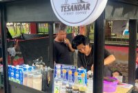 MELAYANI : Ricky pemilik usaha kopi yang berjualan di sekitar lokasi event, Road Race Taman Kota Sampit saat melayani pembeli, Minggu (14/12/2025).(IST)