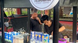 MELAYANI : Ricky pemilik usaha kopi yang berjualan di sekitar lokasi event, Road Race Taman Kota Sampit saat melayani pembeli, Minggu (14/12/2025).(IST)