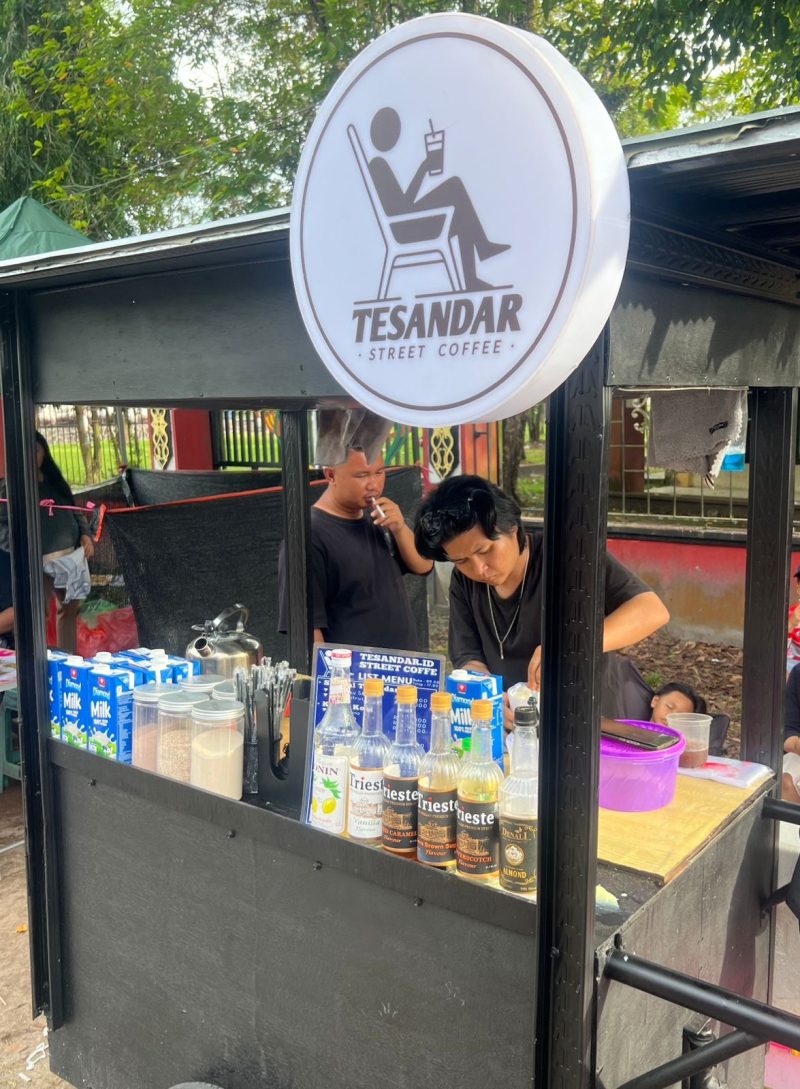 MELAYANI : Ricky pemilik usaha kopi yang berjualan di sekitar lokasi event, Road Race Taman Kota Sampit saat melayani pembeli, Minggu (14/12/2025).(IST)