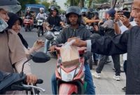 BERBAGI : Ketua PWI Kalteng, M. Zainal,saat membagikan takjil kepada masyarakat yang melintas di depan Kantor PWI Kalteng, Jalan RTA Milono, Palangka Raya, Sabtu (7/3/2026) sore.